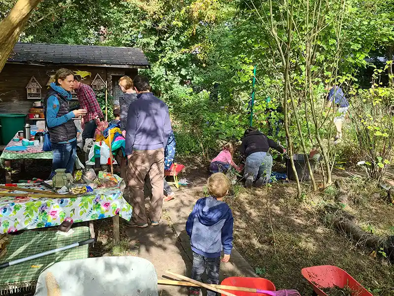 Bei einem Gartentag sind Kinder und Erwachsene bei sonnigem Wetter in dem Schulgarten der Schule Röthmoorweg zu sehen.