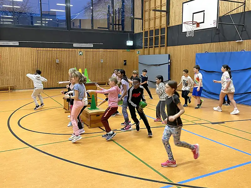 Viele Schulkinder spielen ein Zombieballturnier in einer Sporthalle.